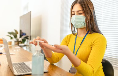 woman wearing mask and using hand sanitizer