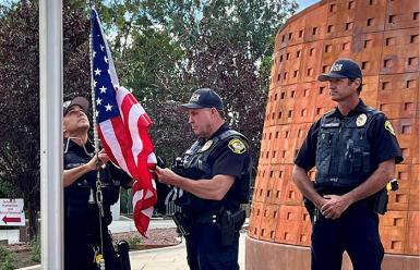 three Saddleback police officers hanging a US flag