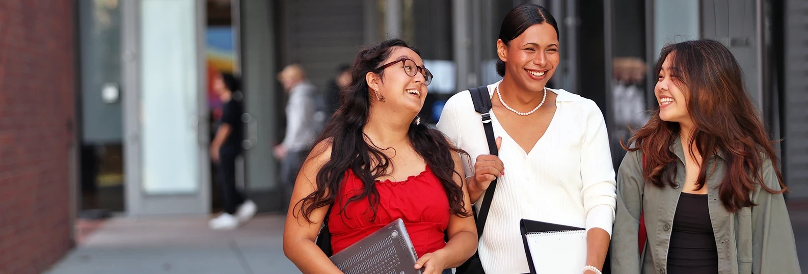 three women walking on campus talking and smiling