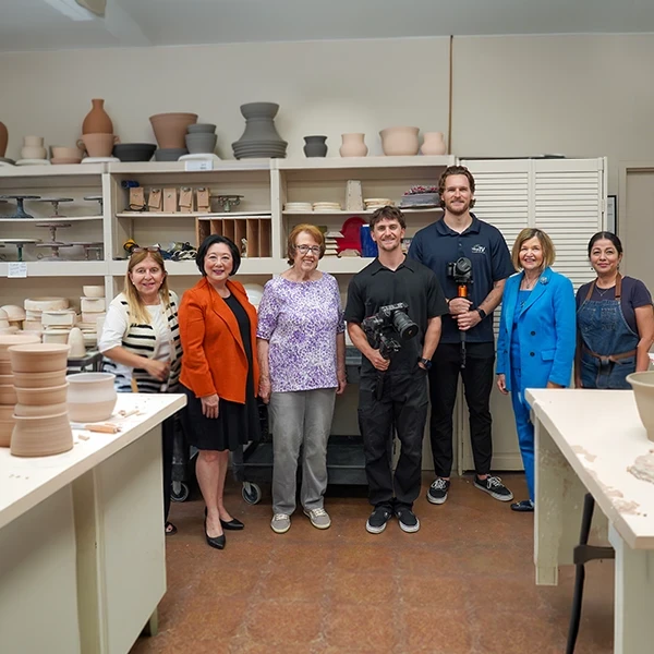 trustees pose with videographers in ceramics class